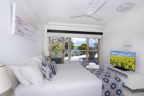 Una habitación de hotel con cama, televisión, balcón y vista al mar.