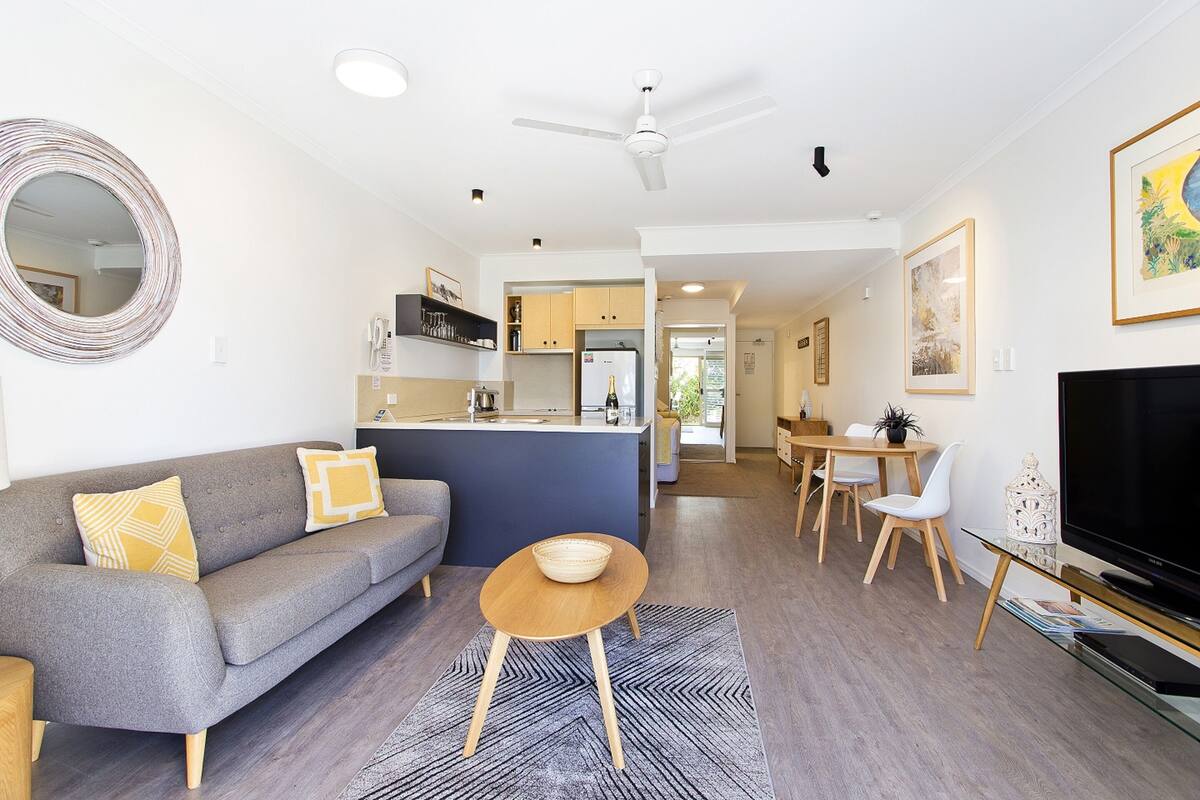 A modern living room with a grey sofa, a round coffee table, and a flat-screen TV.
