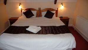 A double bed with a brown quilt, two nightstands, and a white radiator.
