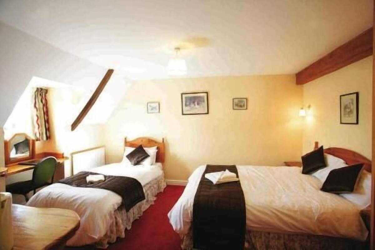 A hotel room with two beds, a desk, and a chair.