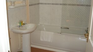 A bathroom with a sink, a bathtub, and a shower area.