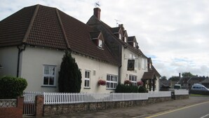A two-story house with a white facade, a tiled roof, and a white picket fence.