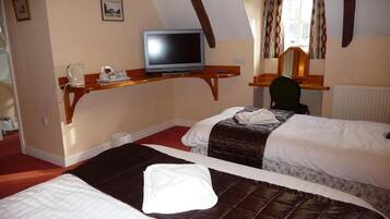 A hotel room with two beds, a desk with a computer, a chair, and a window with curtains.