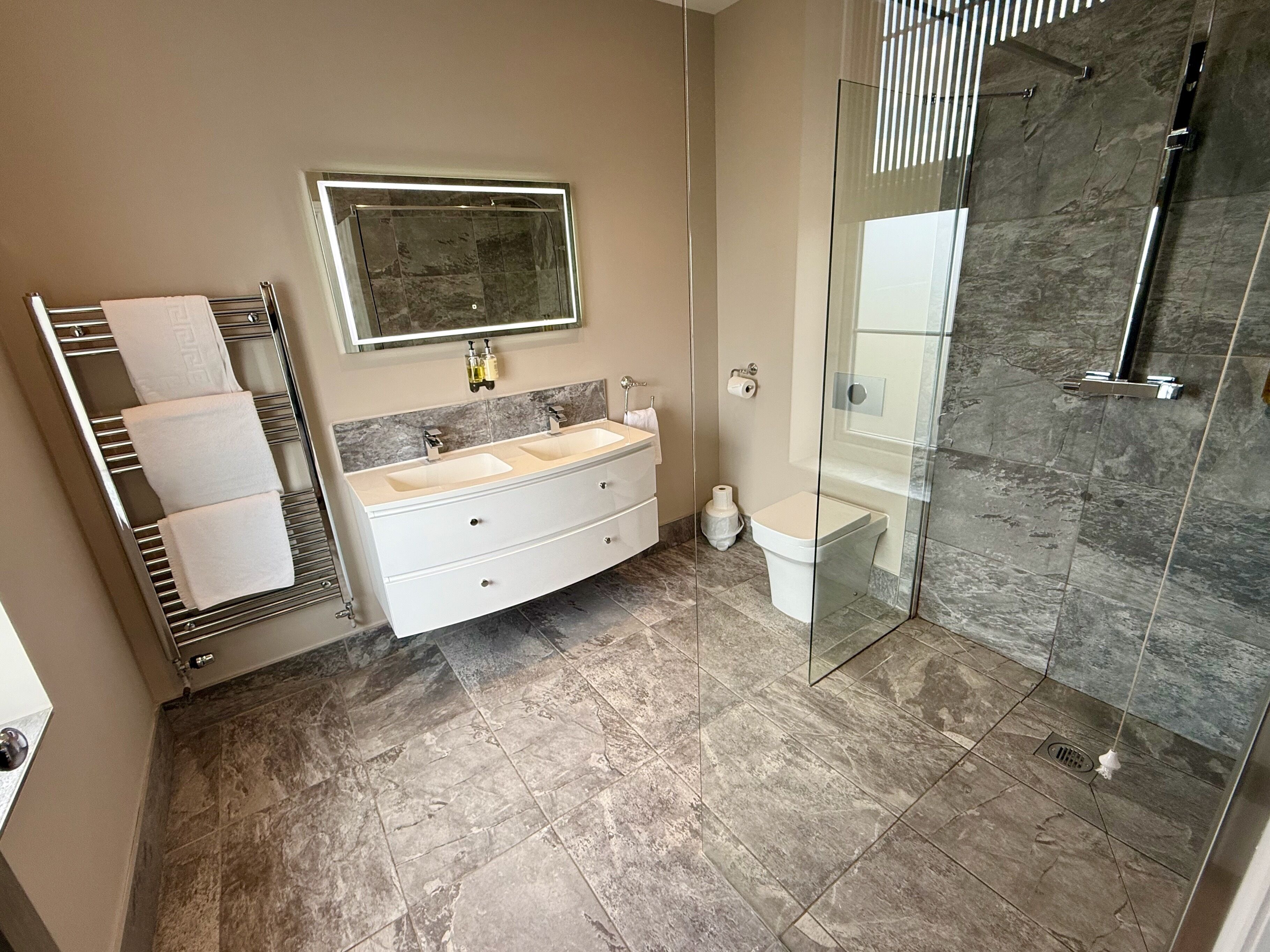Un baño moderno con cabina de ducha de vidrio, tocador doble y barra para toallas.