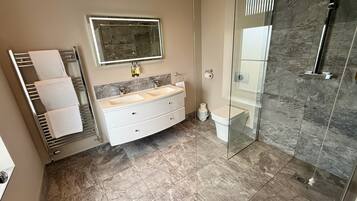 Un baño moderno con cabina de ducha de vidrio, tocador doble y barra para toallas.