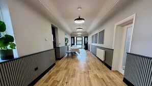 A hallway with wooden flooring, black and white railings, and a table with chairs at the end.