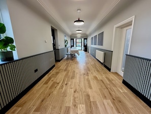 Un couloir doté d’un plancher en bois, de rampes noires et blanches, et d’une table avec des chaises à l’extrémité.