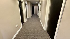A hallway with patterned carpet, white walls, and doors leading to rooms.