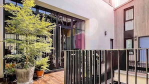 A modern building with large windows, a wooden deck, and potted plants. - ibis Styles Paris La Defense Courbevoie (Courbevoie)