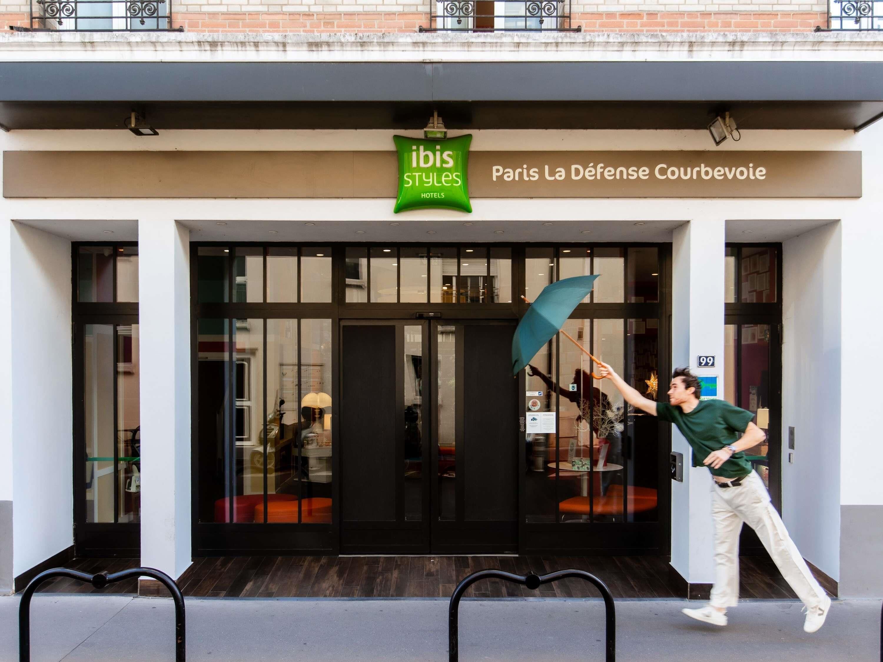 Een hotelentree met een bordje voor 'Ibis Styles Hotels' en 'Paris La Défense Courbevoie'.