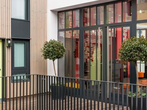 A modern building with a glass facade, a wooden exterior, and a metal railing. - ibis Styles Paris La Defense Courbevoie (Courbevoie)
