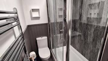 Un baño moderno con ducha de vidrio, inodoro y toallero empotrado.