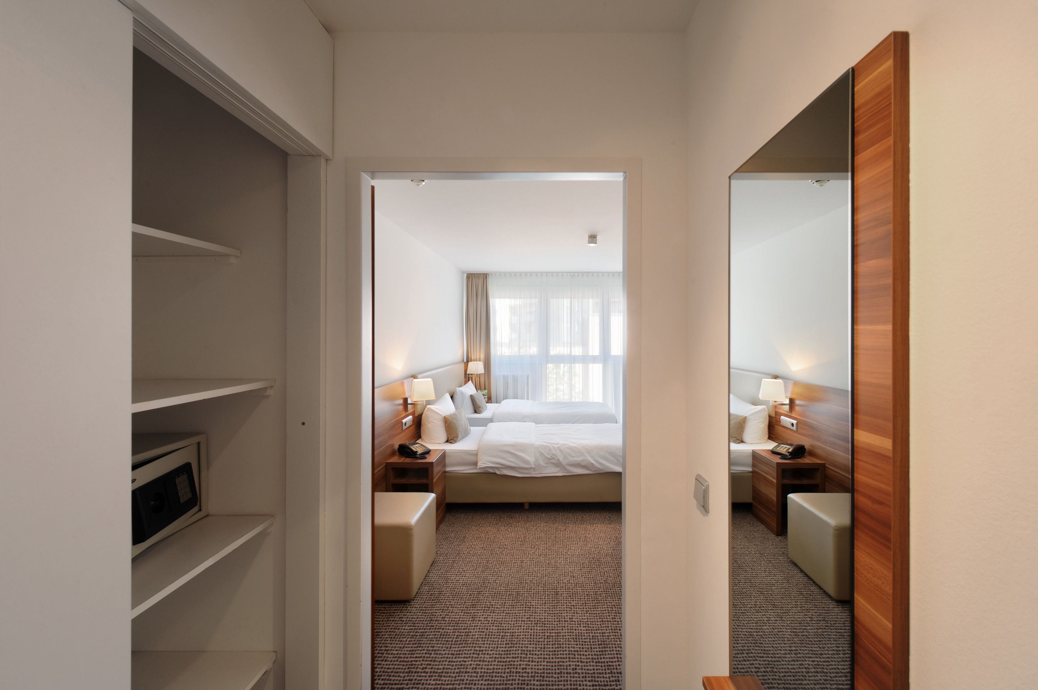Una habitación de hotel con cama, mesitas de noche, lámpara y armario.