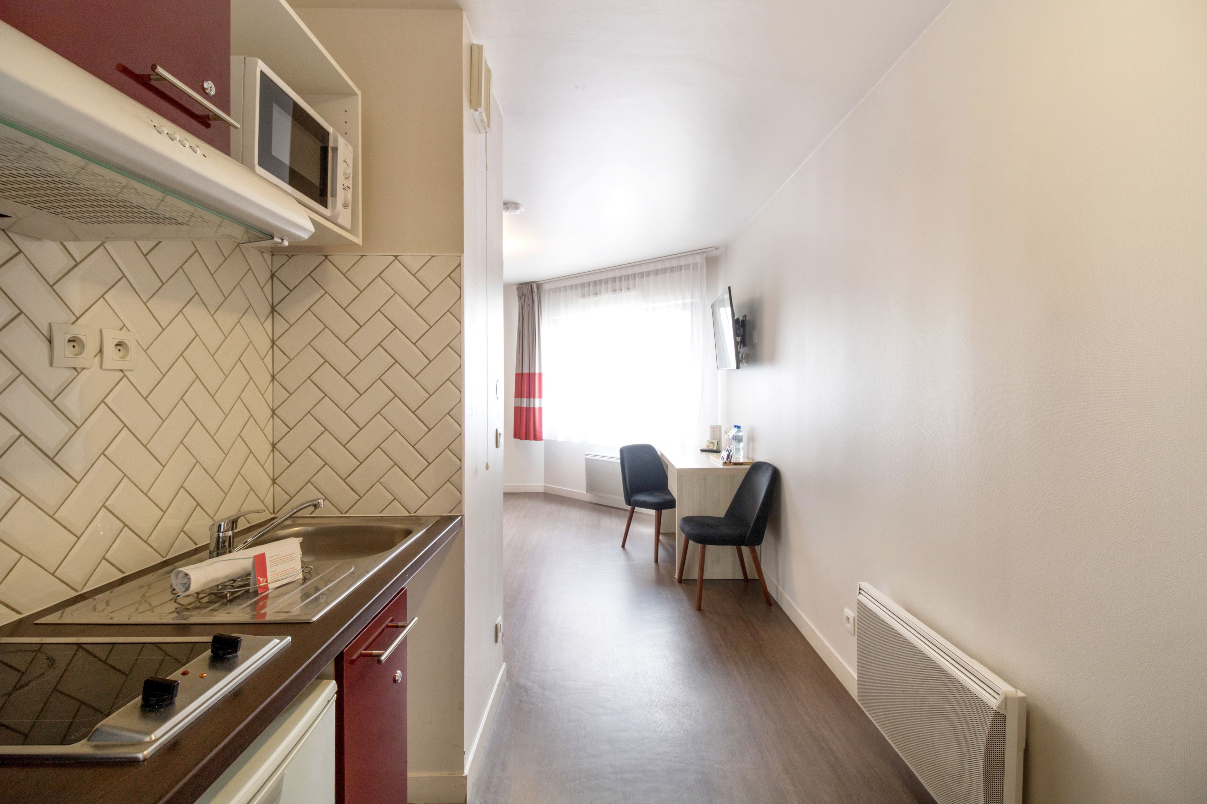 Une cuisine moderne équipée d’un four à micro-ondes, d’une cuisinière et d’un évier. On y trouve également un coin repas avec deux chaises et une table.