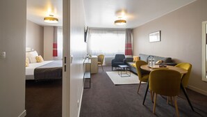 Una habitación de hotel con cama, escritorio, sofá y zona de comedor con sillas.