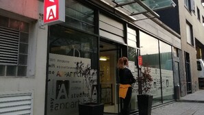 Un edificio moderno con entrada de vidrio y un letrero rojo que indica una galería de arte.