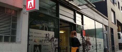 A modern building with a glass entrance and a red sign indicating an art gallery.