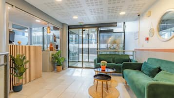 A reception area with a green sofa, a round coffee table, and a reception desk.