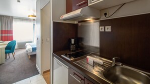 Cocina de hotel compacta con microondas, estufa, fregadero y cafetera.