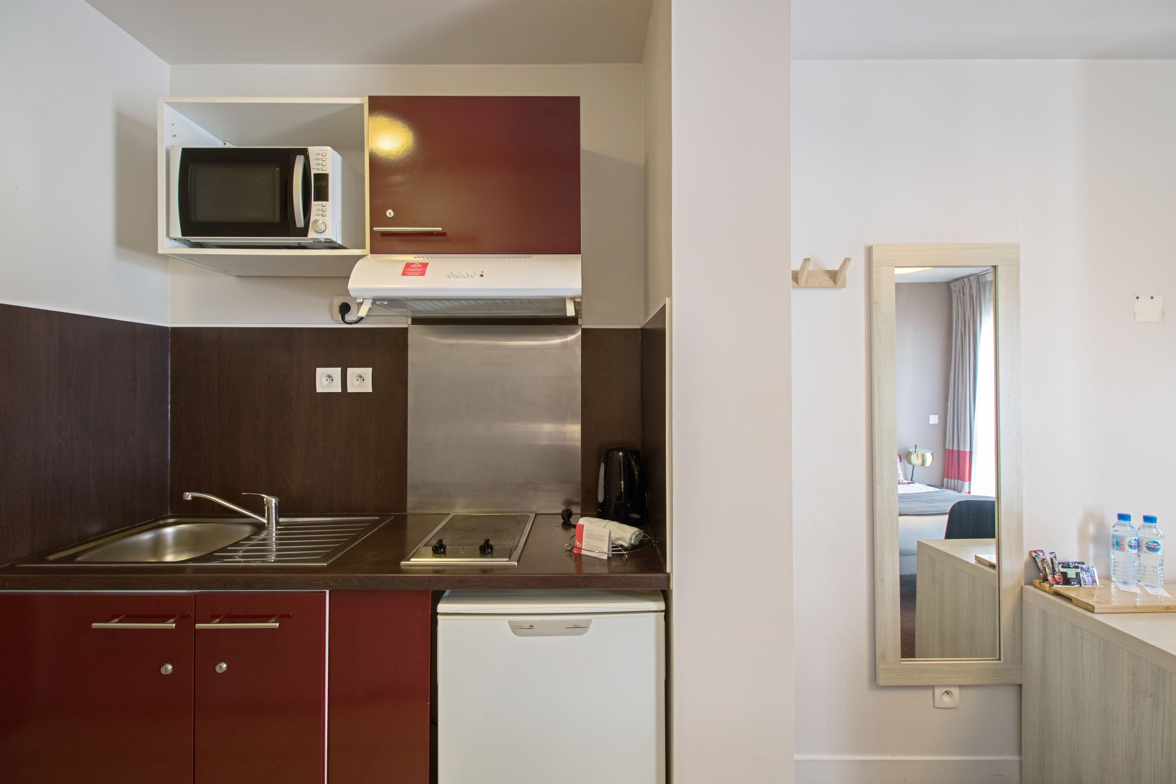 A compact kitchenette with a microwave, stove, sink, and a small refrigerator.