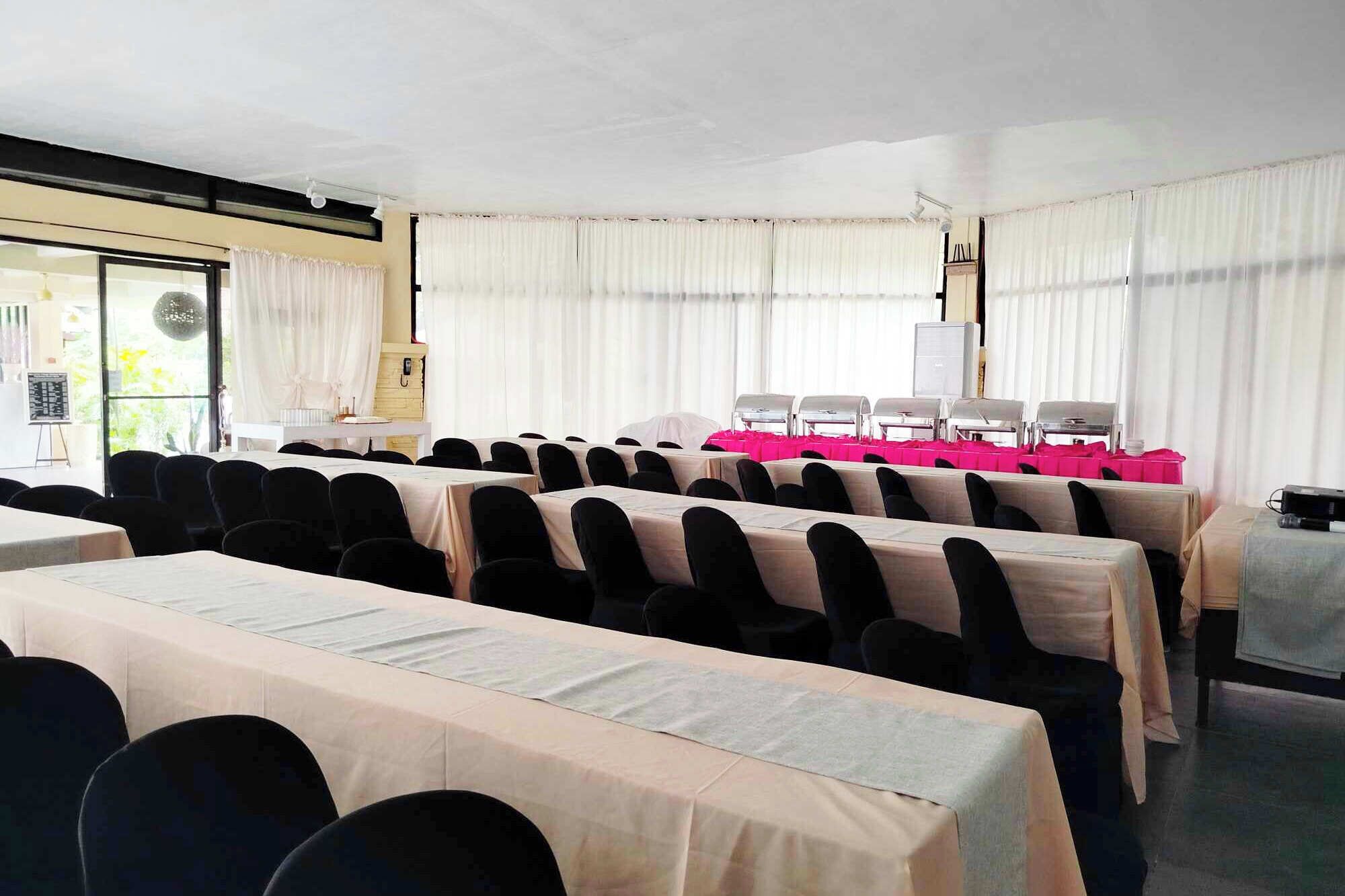 A conference room with rows of tables, chairs, and a projector.
