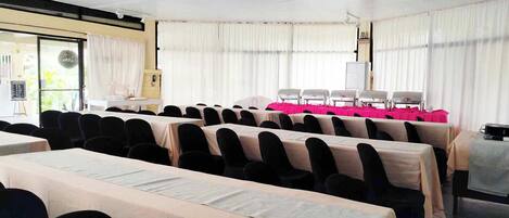 A conference room with rows of tables, chairs, and a projector.