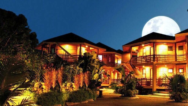 Un hotel con varias edificaciones, una gran luna en el cielo y alrededores bien iluminados.