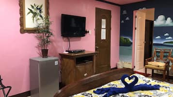 Relax in a cozy space with a comfortable bed, a TV, and a small refrigerator.