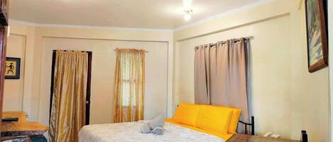 A bedroom with a bed, a desk, and curtains.