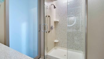 Un baño moderno con cabina de ducha de vidrio, una bañera blanca y una puerta de vidrio.