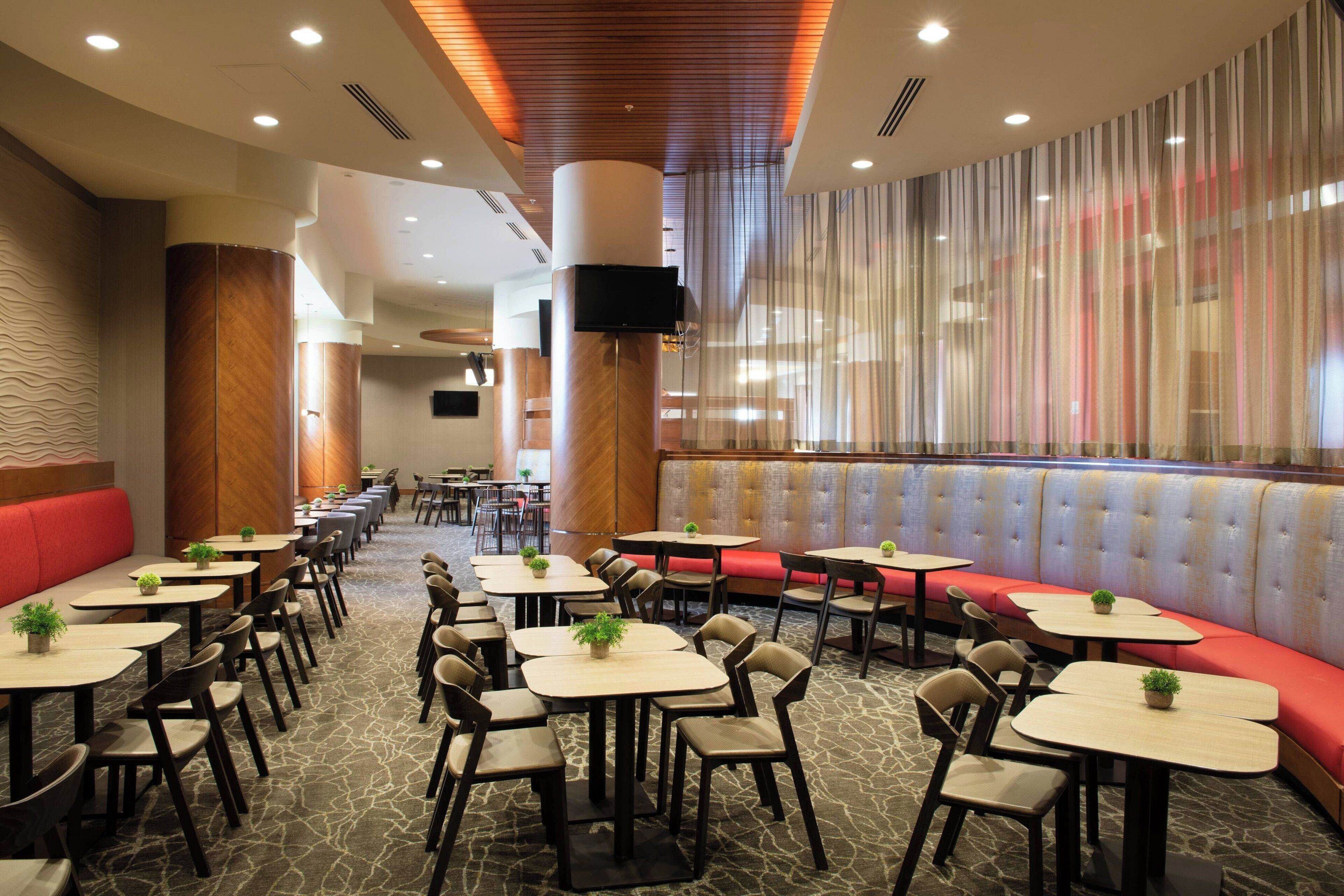A restaurant with multiple seating areas, including booths and tables, and a large window with curtains.