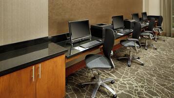 A conference room with multiple desks, each equipped with a laptop and a printer.