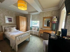 A bedroom with a bed, a desk, a chair, a wardrobe, and a window.