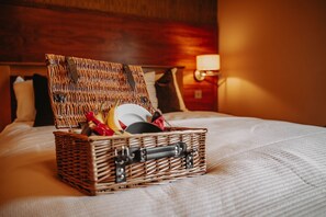 A wicker basket with a handle on a bed.