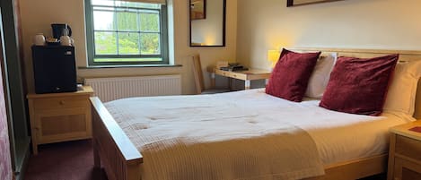 A bedroom with a bed, a desk, a chair, a radiator, a window, and a mirror.