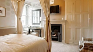 A bedroom with a four-poster bed, a fireplace, a desk, and a television. - The Old Orleton Inn (Telford)