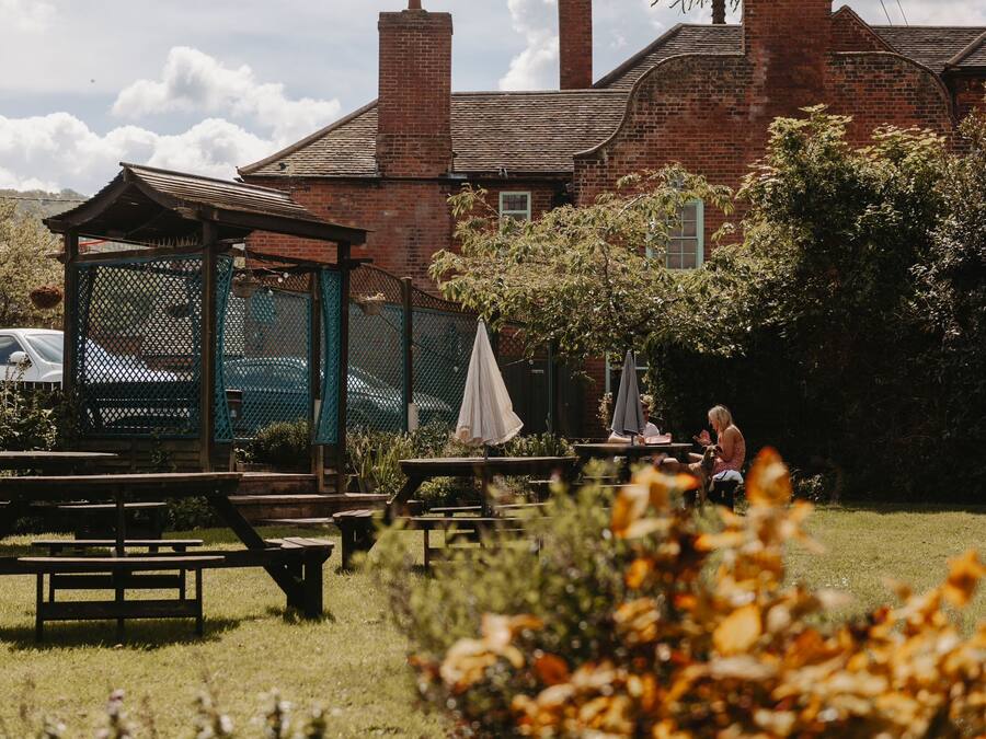 A garden with picnic tables and a gazebo, surrounded by brick buildings.