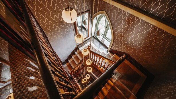 A staircase with wooden railings and a patterned wall. - The Old Orleton Inn (Telford)