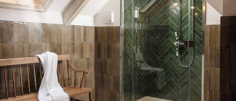A shower with a glass door and a herringbone tile pattern on the walls.