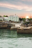 Una propiedad frente al agua con un muelle, un edificio que dice "Pier House" y un atardecer de fondo.