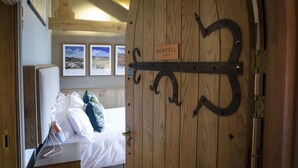Una puerta de madera con un letrero que dice "BOWFELL 295ft" y una cama con ropa blanca y almohadas.
