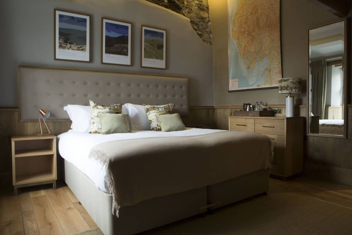 A bedroom with a large bed, a nightstand, a dresser, and a map on the wall.