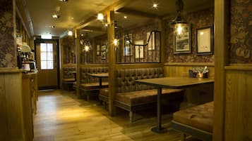 A restaurant interior with wooden booths, tables, and a patterned wallpaper design.