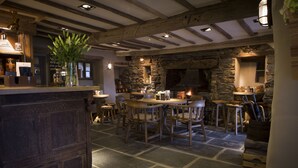 Un interior rústico con chimenea de piedra, muebles de madera y una zona de bar.
