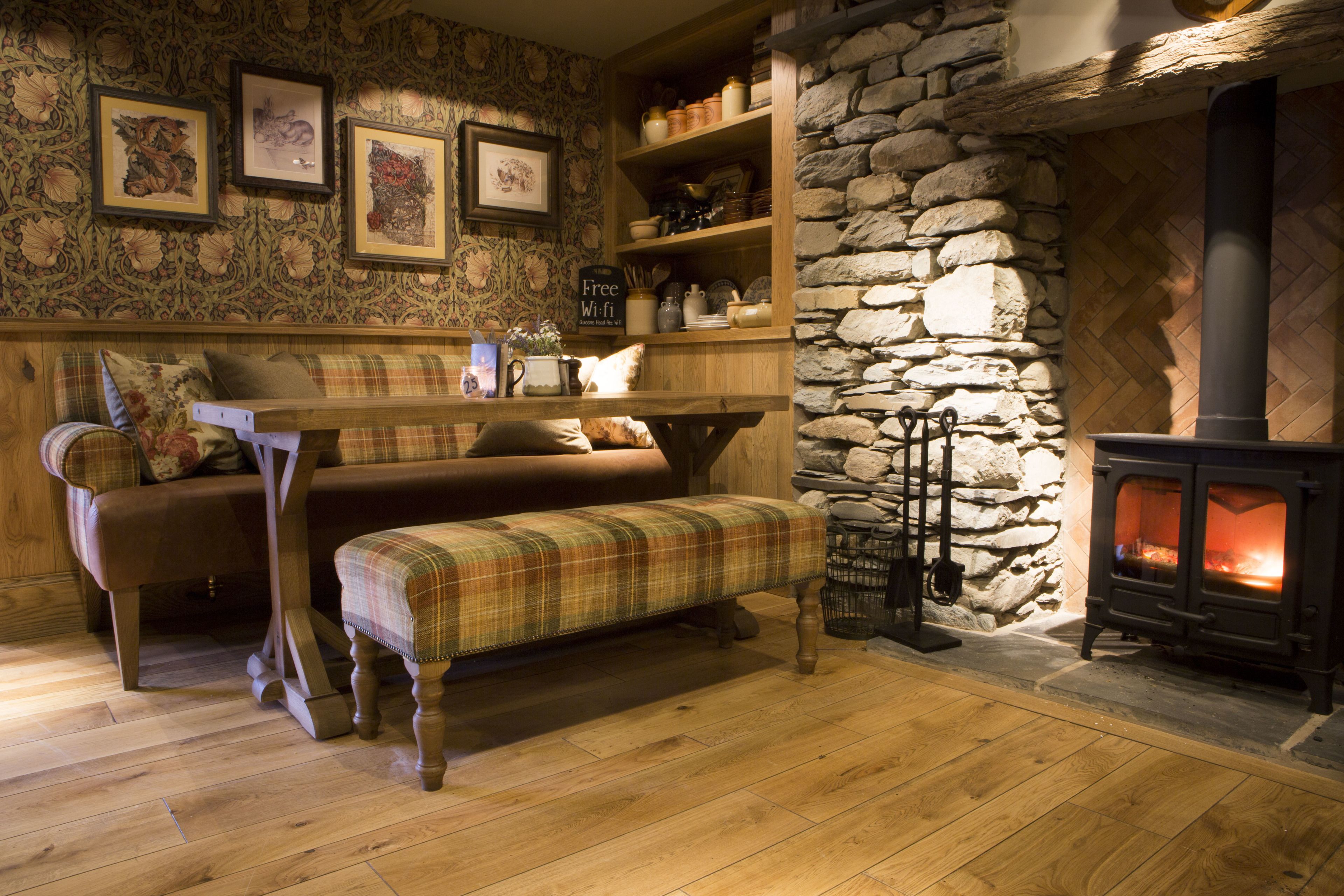 A cozy room with a stone wall, wooden furniture, a bench, and a fireplace.