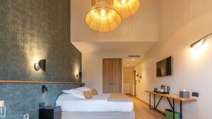 Une chambre d’hôtel moderne, dotée d’un grand lit, de tables de chevet, d’un bureau et d’une télévision.