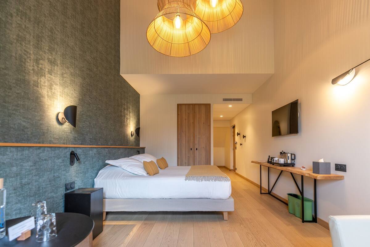 Ein modernes Hotelzimmer mit einem großen Bett, Nachttischen, einem Schreibtisch und einem Fernseher.