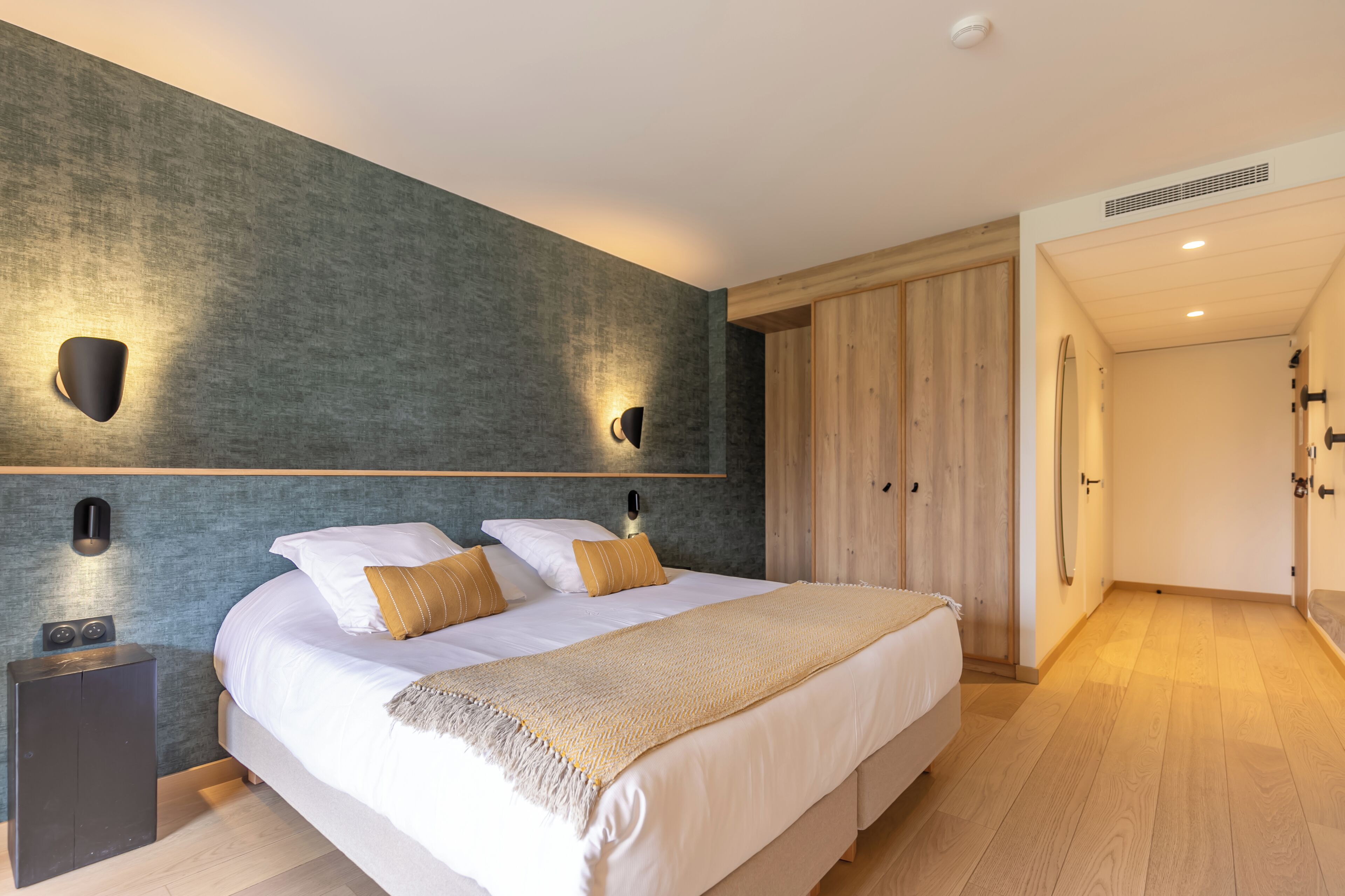 Une chambre à coucher moderne avec un grand lit, deux tables de chevet, une armoire et un dressing.