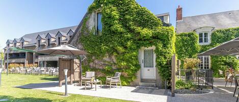 A building with ivy-covered walls, outdoor seating, and a gravel patio.