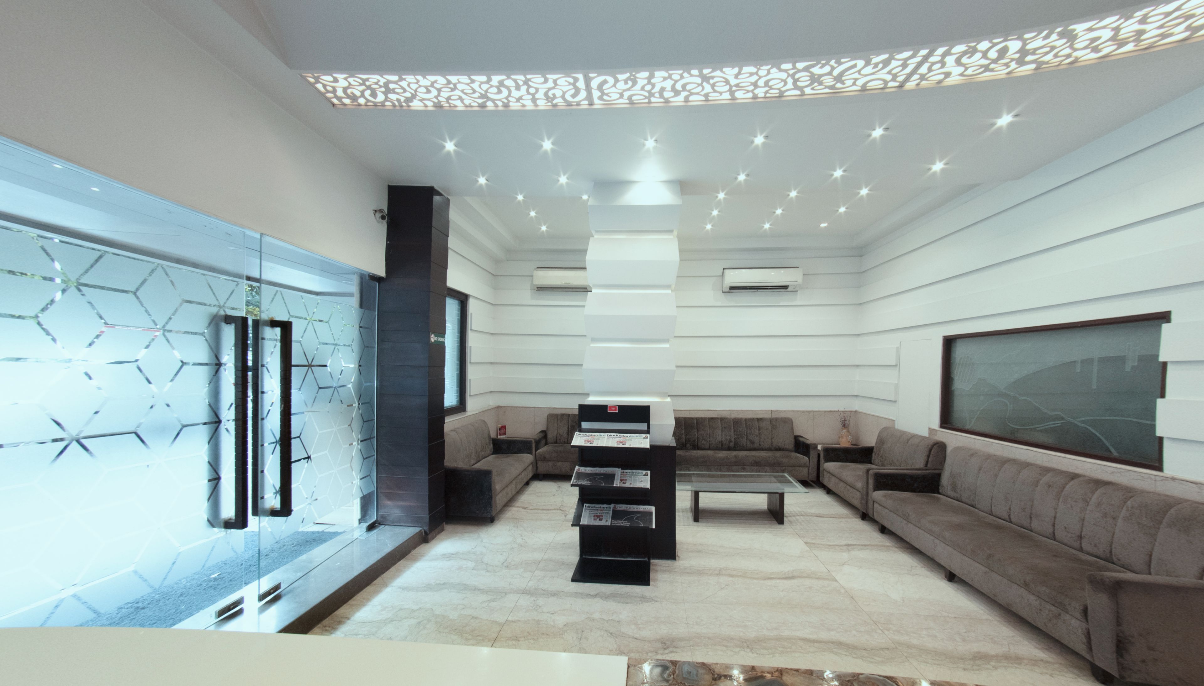 A modern living room with a glass partition, a fireplace, and a sofa set.